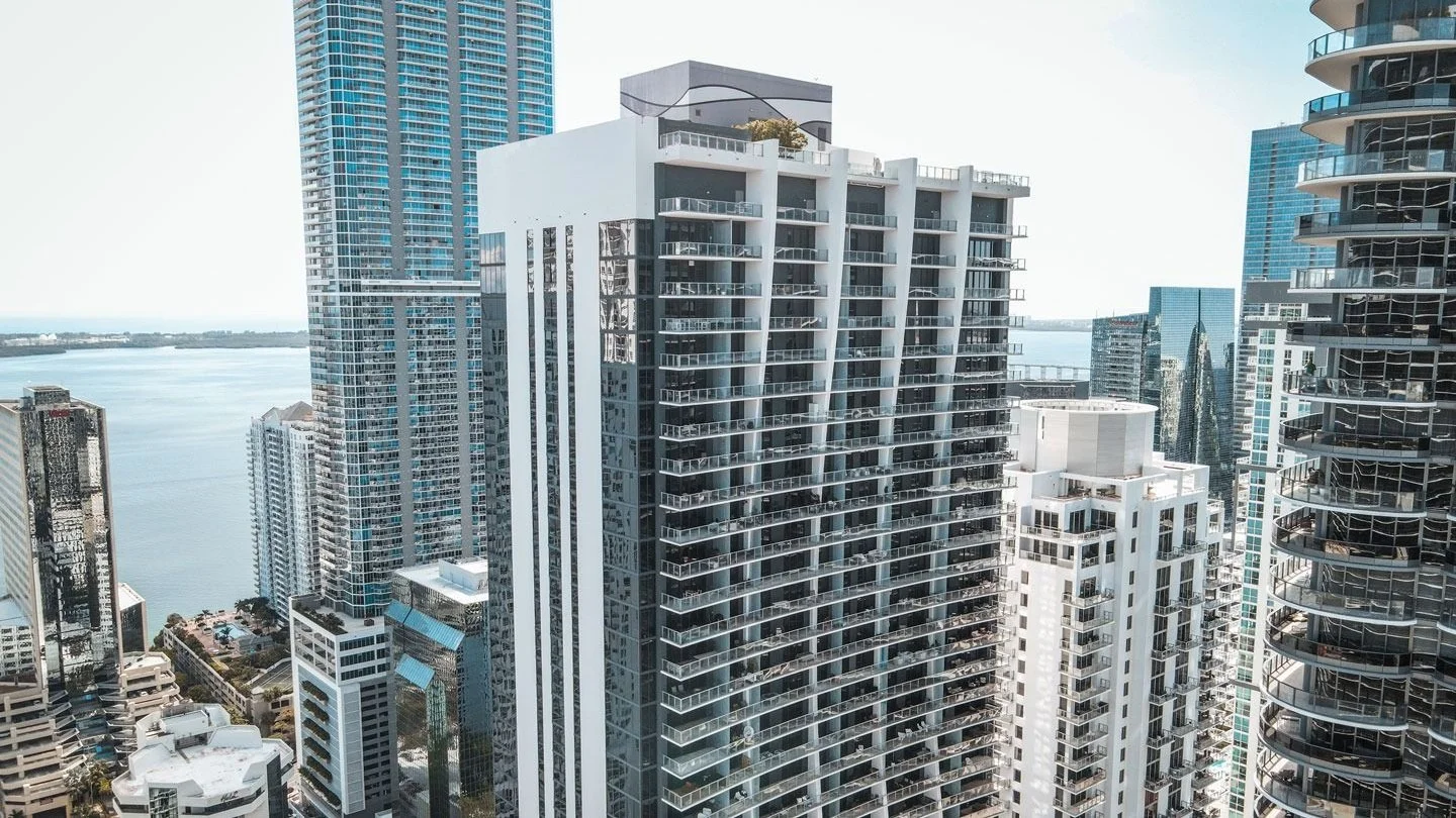 The 1010 Brickell condo tower seen from above among neighbouring Brickell towers, with Biscayne Bay behind.
