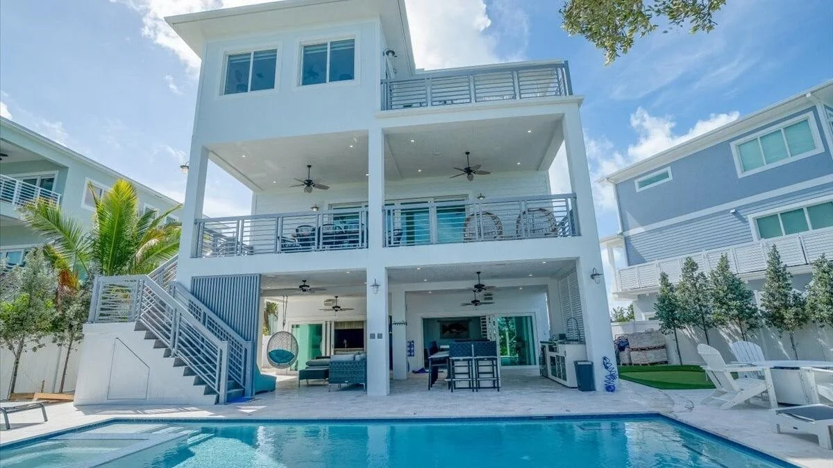 Three-storey white vacation rental home with balconies and a pool in the Florida Keys