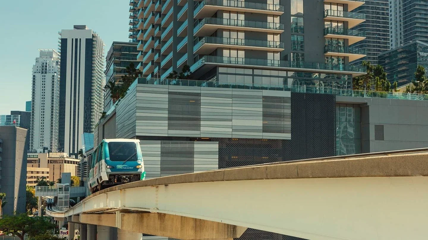 A Metromover train passing Brickell high-rises on its elevated track; the photo shows the Brickell neighbourhood, not Axis on Brickell.
