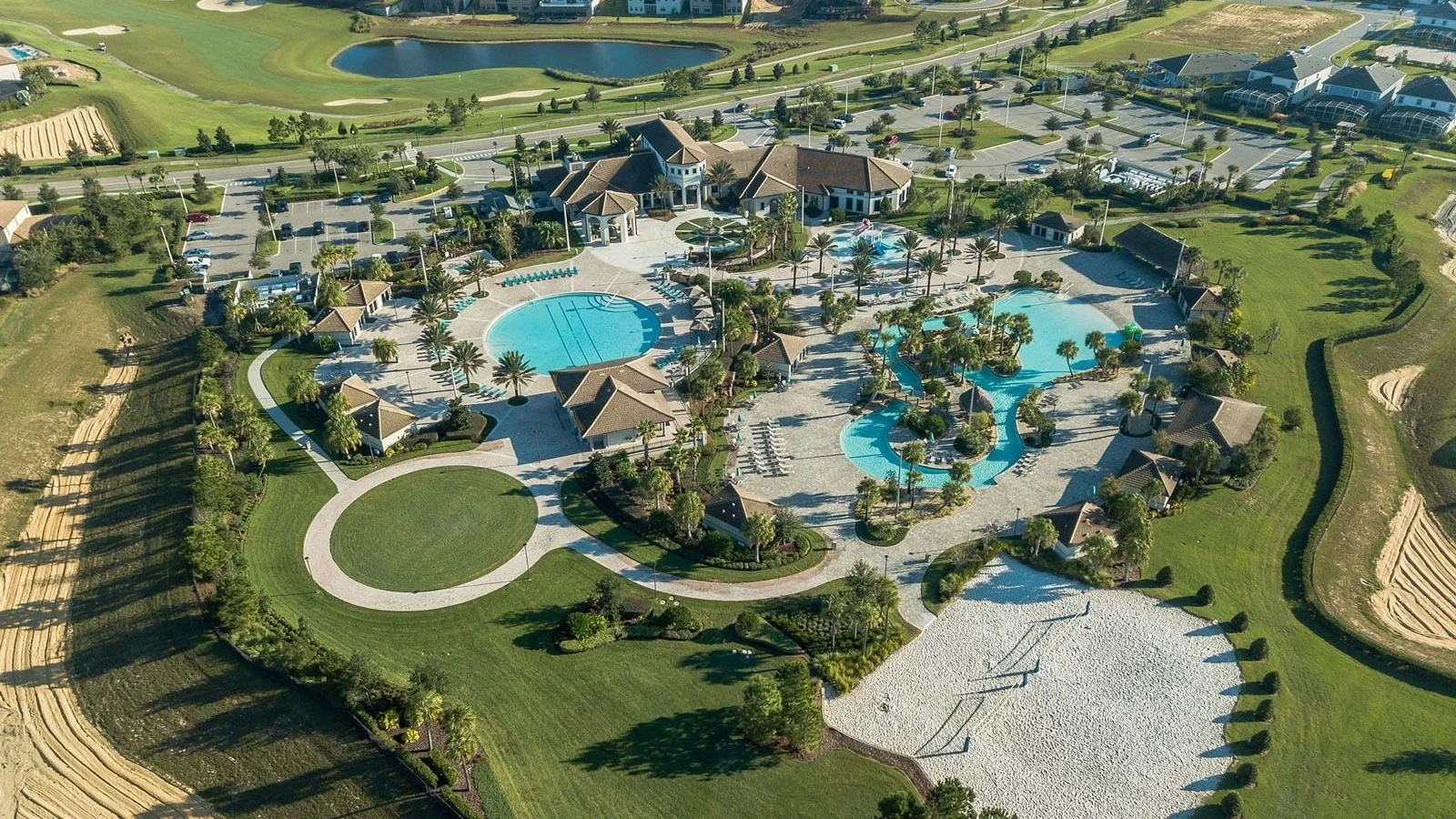 Aerial view of the Oasis Club pools, lazy river and clubhouse beside the golf course at ChampionsGate.