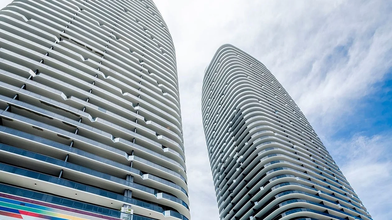 The two rounded Brickell Heights towers with curved white balconies against a cloudy sky.