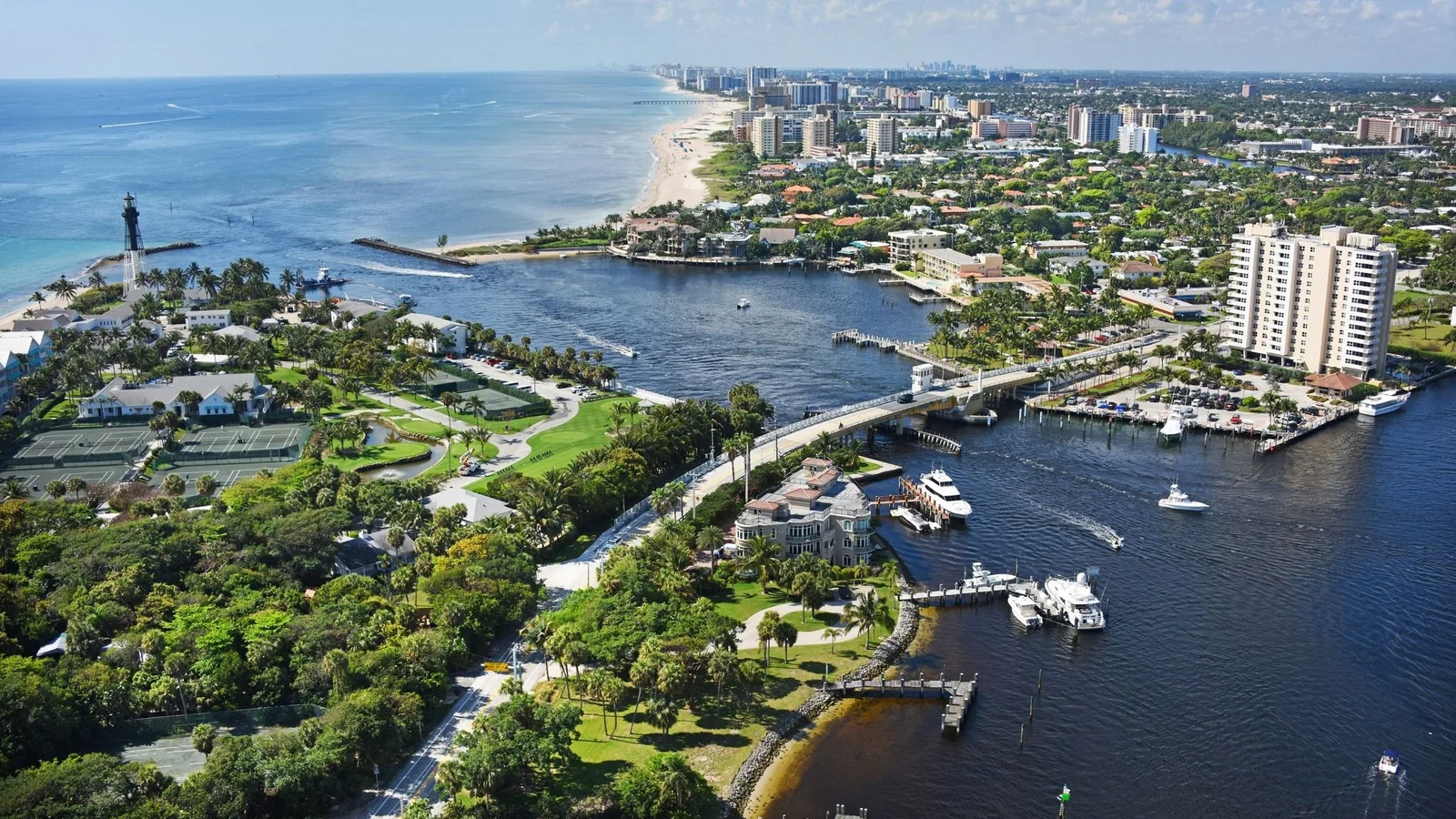 Aerial view of Hillsboro Inlet in Pompano Beach with homes, a condo tower and the lighthouse