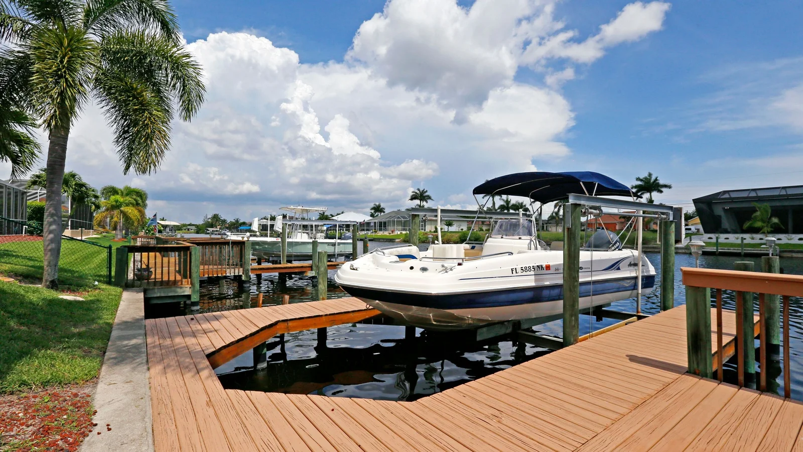Private dock with a boat on a lift behind a waterfront home on a Cape Coral canal