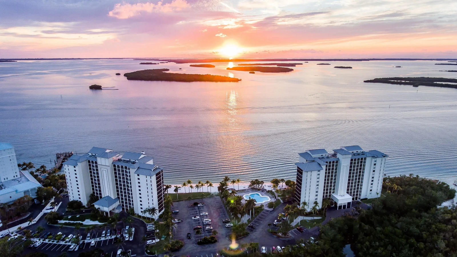 Aerial view of two condo towers on Estero Bay near Fort Myers Beach at sunset.