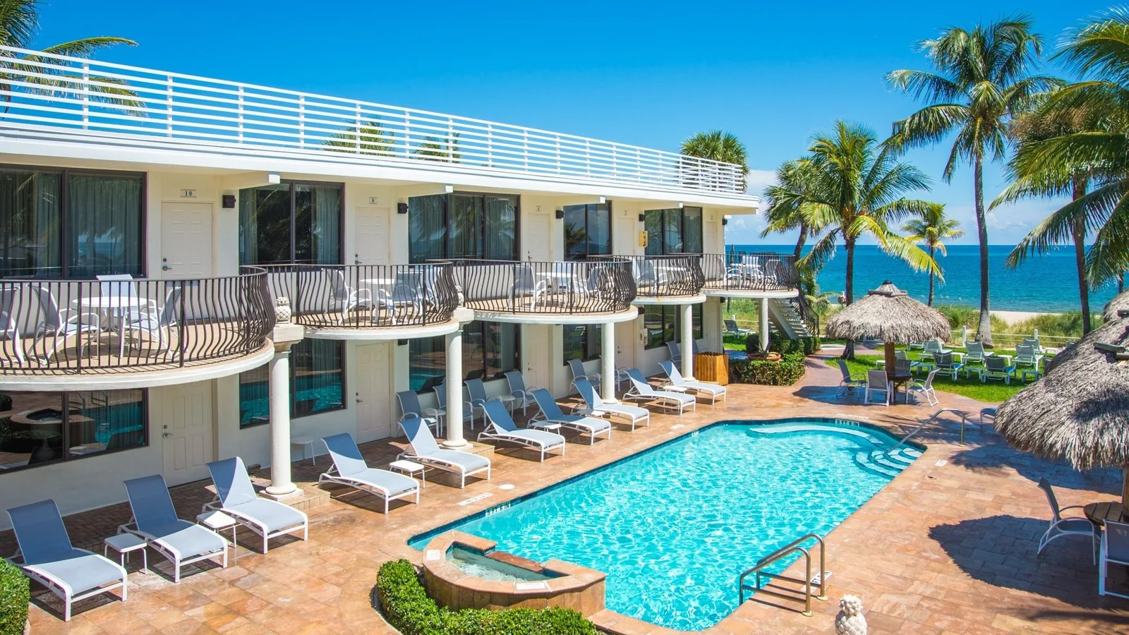 Two-storey beach motel with balconies around a pool near the ocean in Lauderdale-by-the-Sea