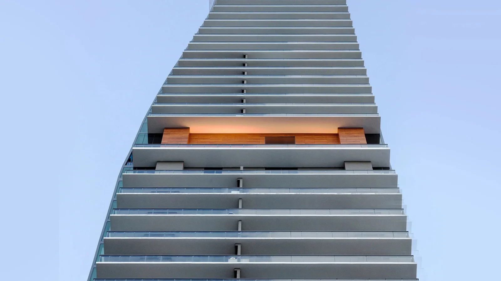 The top of the Echo Brickell tower with its stepped balconies and a wood-lined terrace against a clear sky.