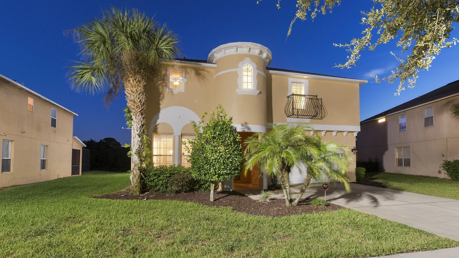 Two-story Mediterranean-style vacation home at dusk at Emerald Island Resort in Kissimmee.