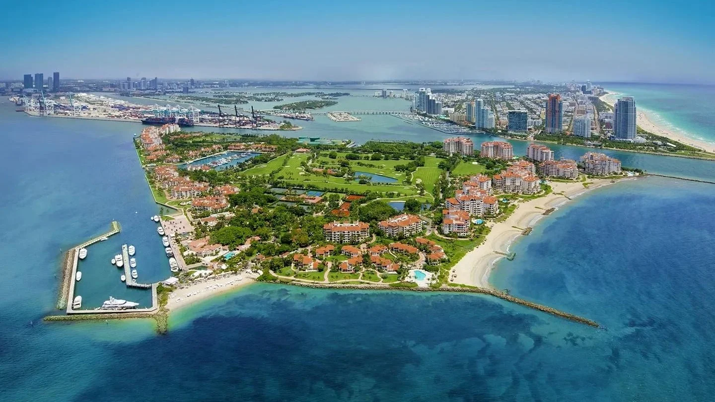 Aerial view of Fisher Island with its marina and residences, Miami Beach towers behind