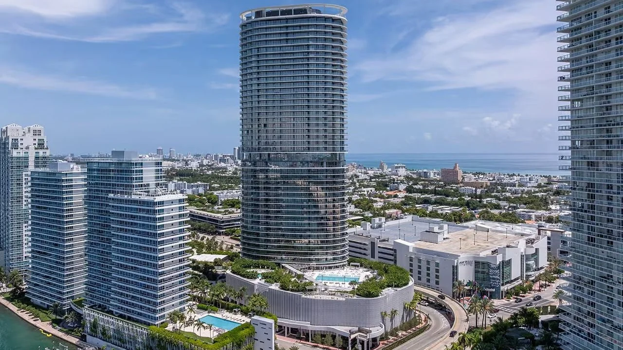 Aerial view of the elliptical Five Park tower rising over South Beach, with the ocean in the distance