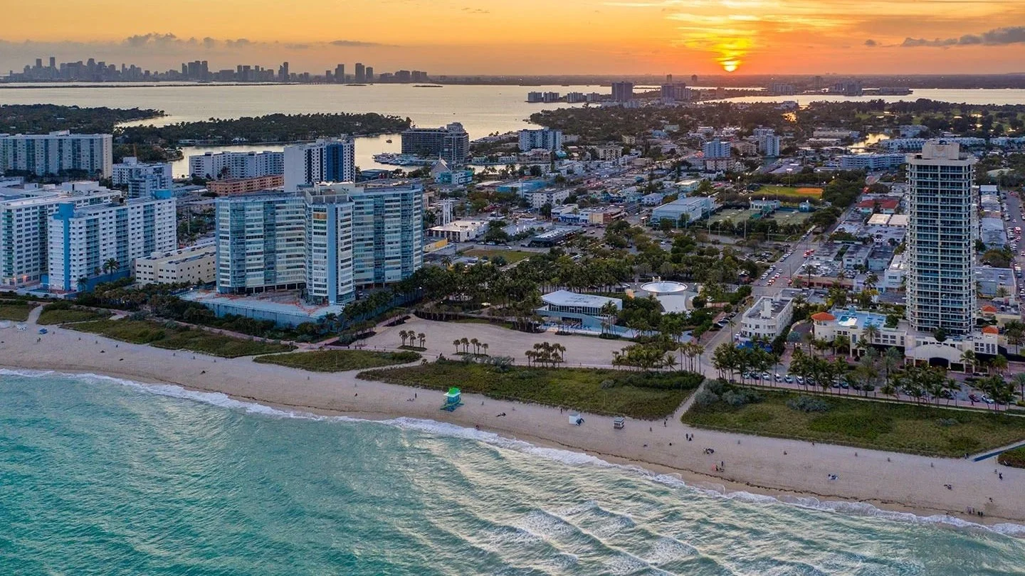 Aerial view of North Beach in Miami Beach with condo buildings behind the sand at sunset
