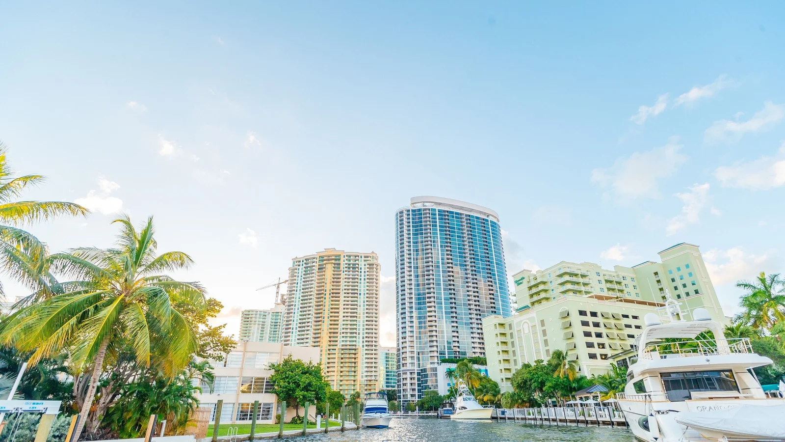 Fort Lauderdale condo towers above palm trees and moored yachts on the New River