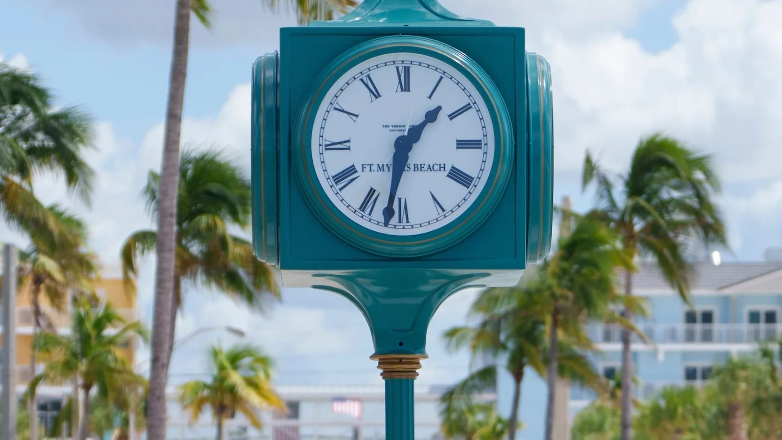 Street clock at Times Square in Fort Myers Beach with palm trees and colorful buildings