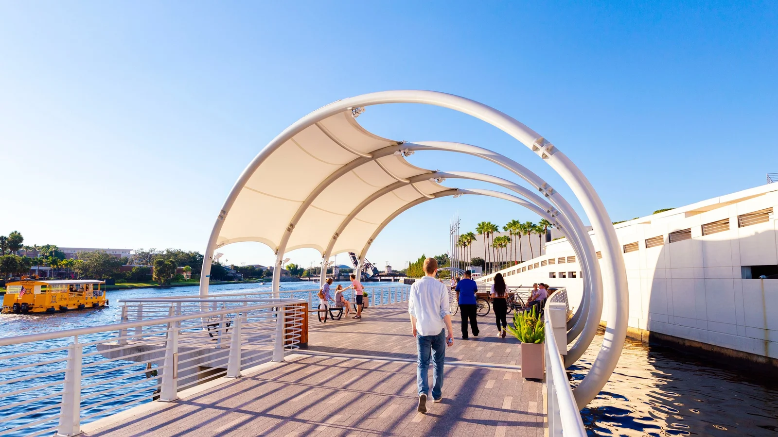 Tampa Riverwalk with a shade canopy, strollers and a water taxi on the Hillsborough River
