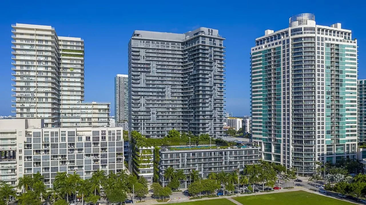 The Hyde Midtown tower with an H sign on its crown, between neighbouring Midtown Miami towers with green rooftop terraces.