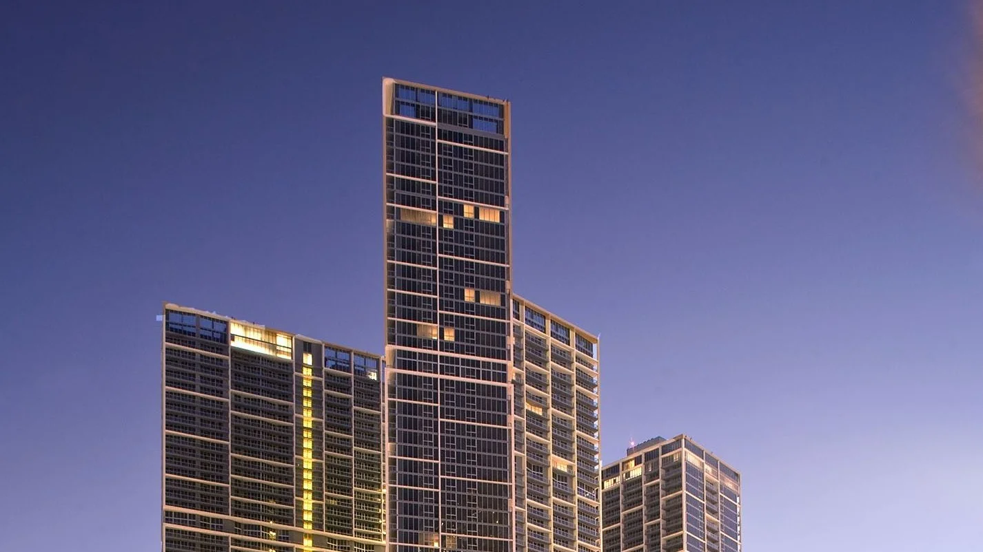 The Icon Brickell towers lit at dusk against a purple evening sky.