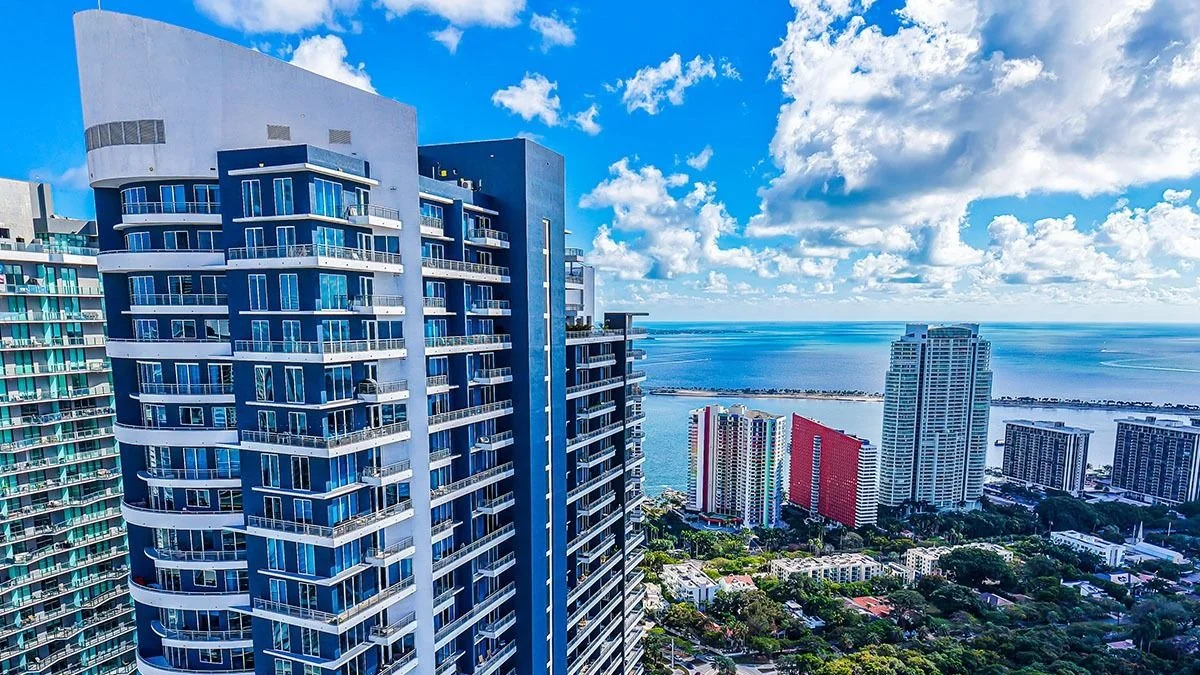 The Infinity at Brickell tower with its blue and white facade, with Biscayne Bay in the distance.