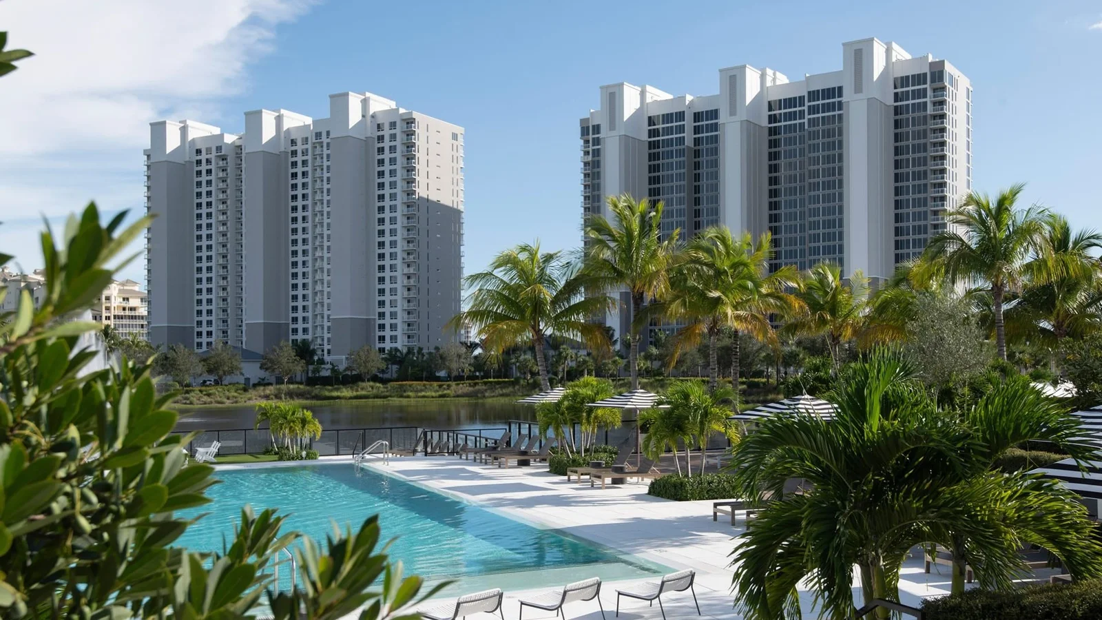 Two Kalea Bay condominium towers behind the palm-lined pool deck in North Naples