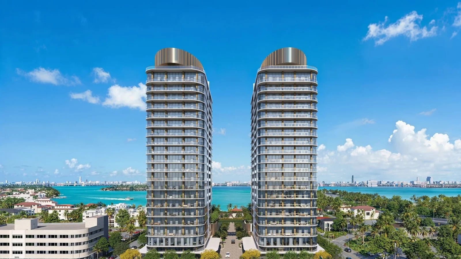 Rendering of the twin Kempinski Residences Miami Design District towers with rounded metal crowns, with Biscayne Bay and a distant skyline behind.