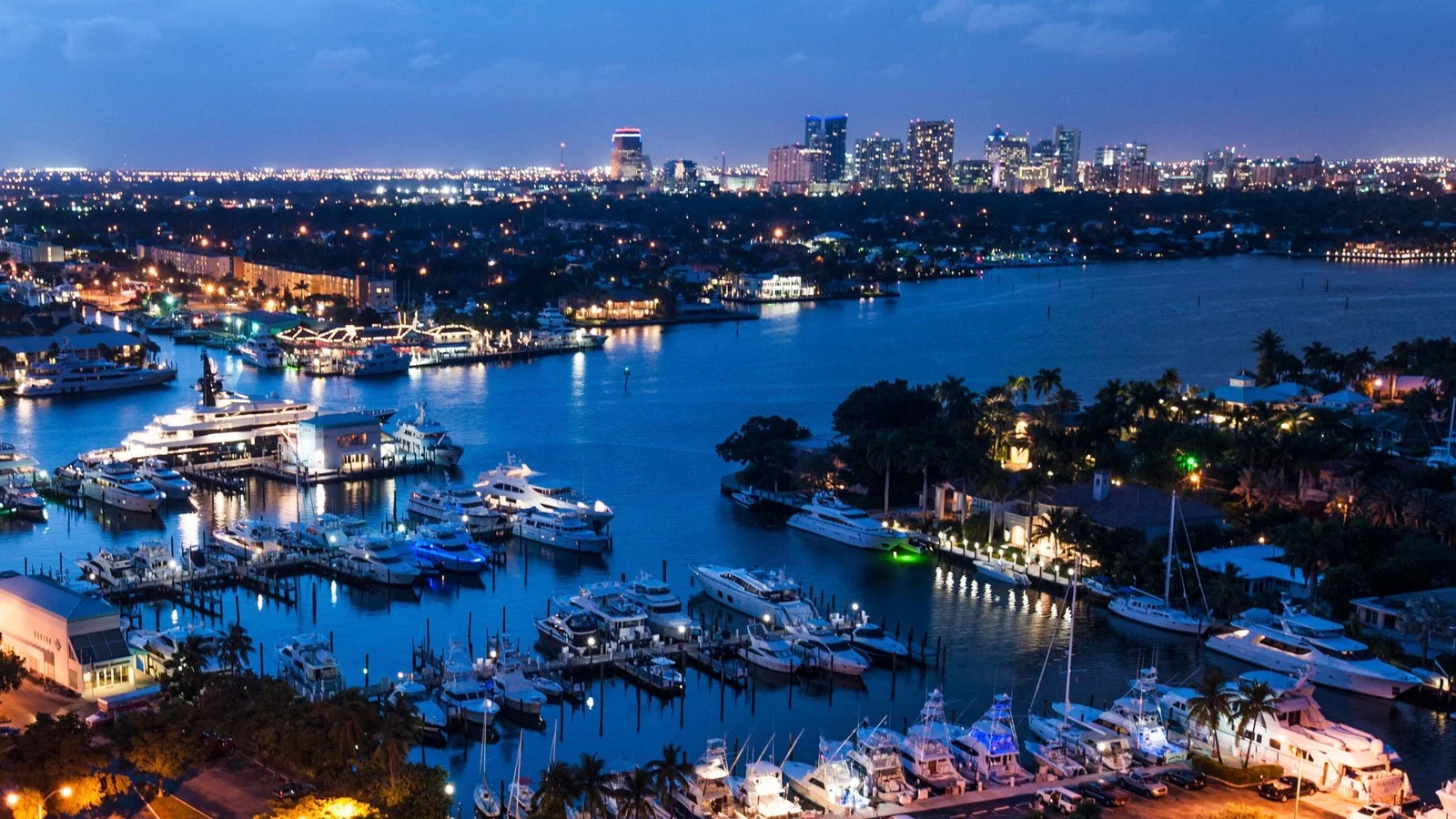 Fort Lauderdale marinas and waterways at night with the downtown skyline behind; the photo shows the area, not Lauderdale Tower itself