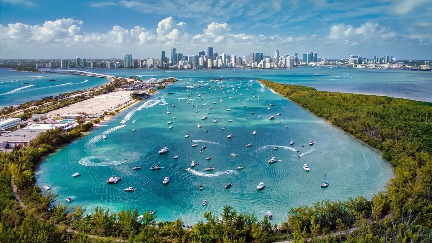 Aerial view of a Key Biscayne lagoon full of boats with the Miami skyline across the bay