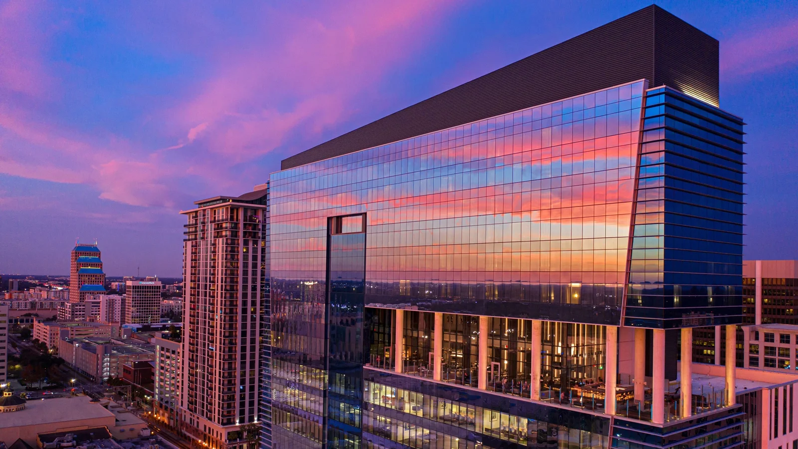 Glass office tower reflecting a sunset sky in downtown Orlando, Florida.