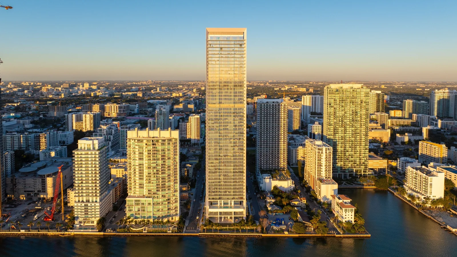 The slim Missoni Baia tower glowing in golden evening light above neighbouring Edgewater buildings by the water.