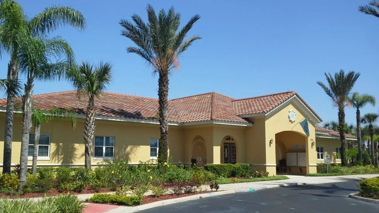 Oakwater Resort clubhouse with a tiled roof and palm trees in Kissimmee.