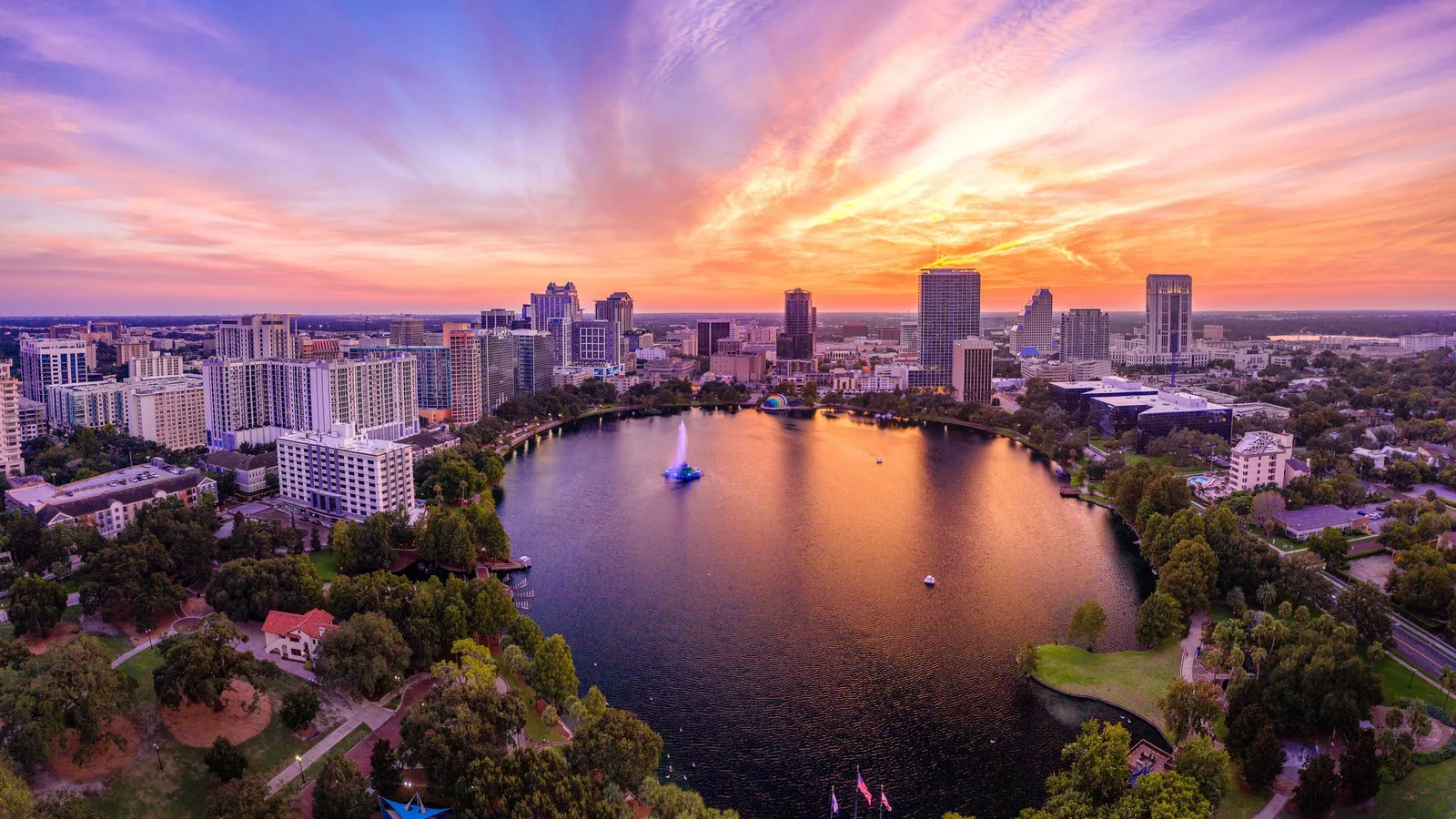 Aerial view of Lake Eola and the downtown Orlando skyline at sunset.