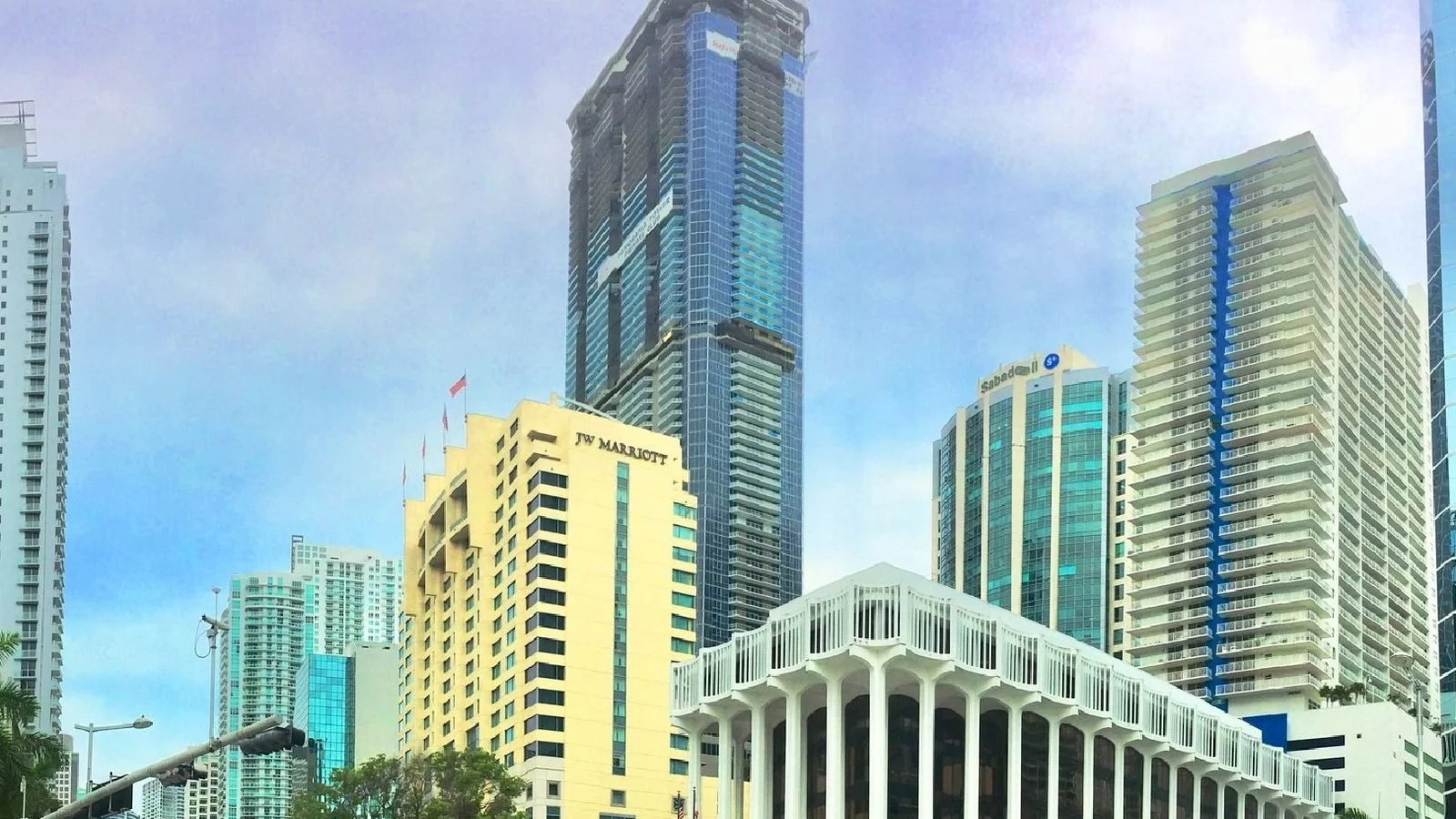 Panorama Tower rising above Brickell Avenue buildings, including the JW Marriott hotel, on a sunny day.