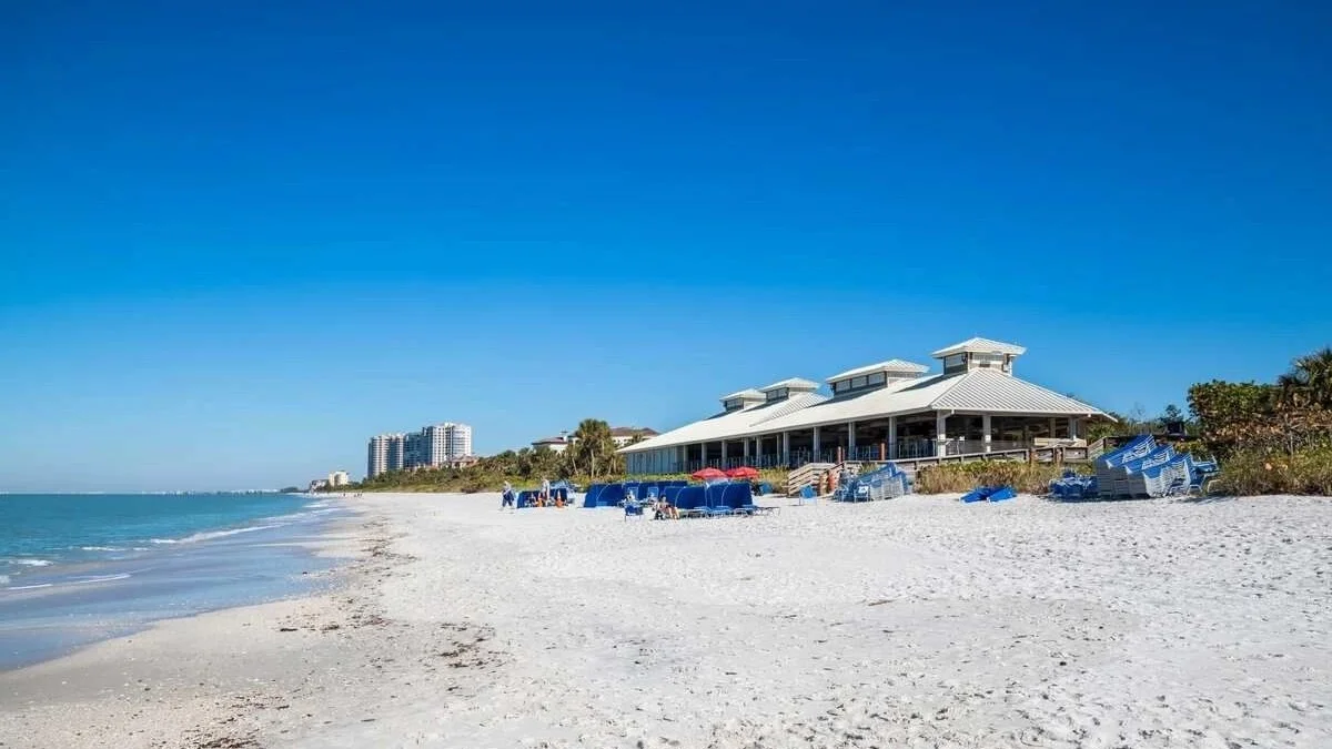 Pelican Bay beach in Naples with the community beach pavilion and condominium towers along the shore in the distance