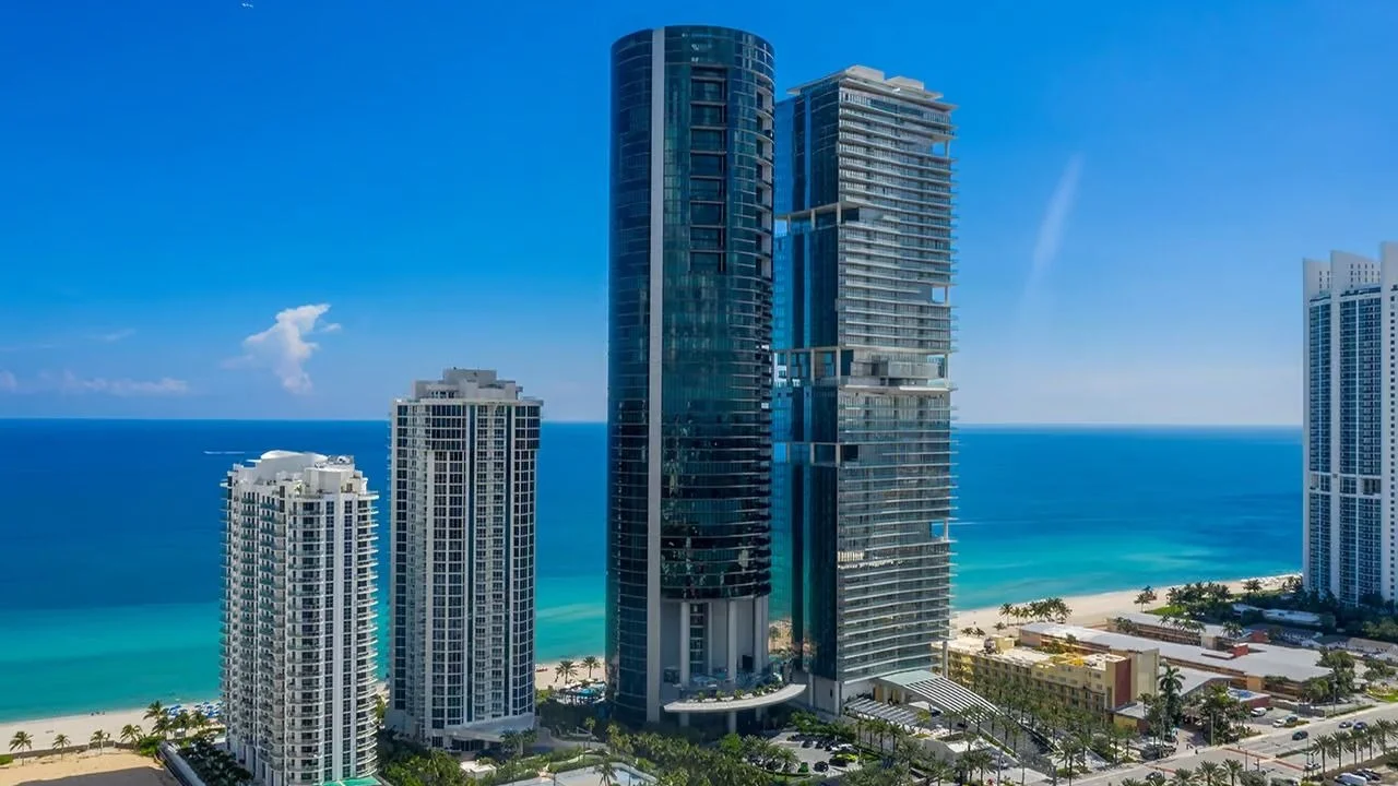 Aerial view of the dark glass cylinder of Porsche Design Tower on the beach in Sunny Isles Beach