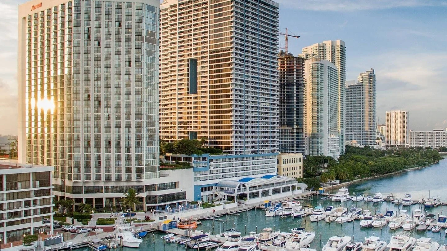 High-rise condo towers and a tower under construction beside a marina on Biscayne Bay in Miami