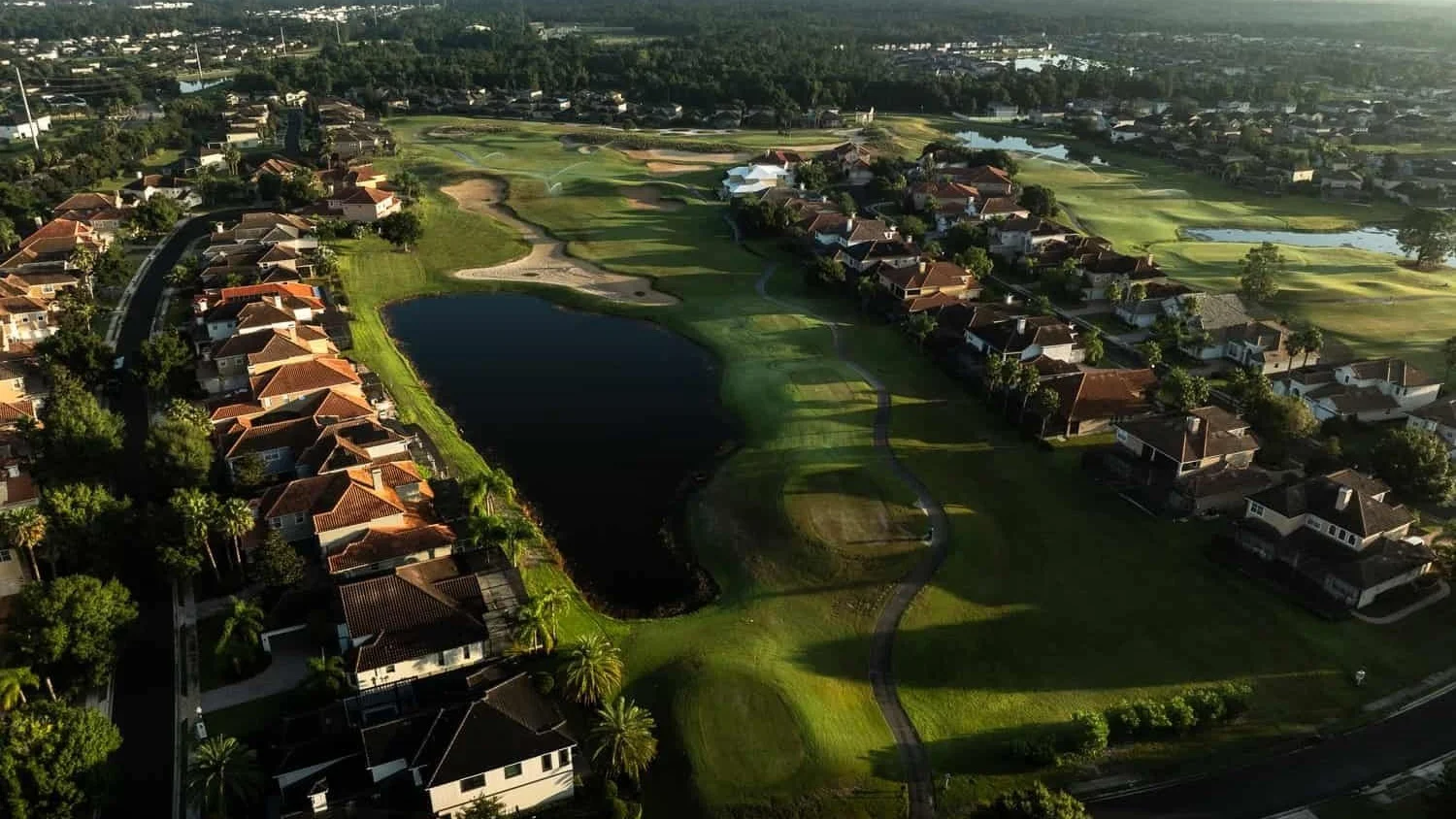 Aerial view of a Providence Golf Club fairway and lake lined with homes in Davenport.