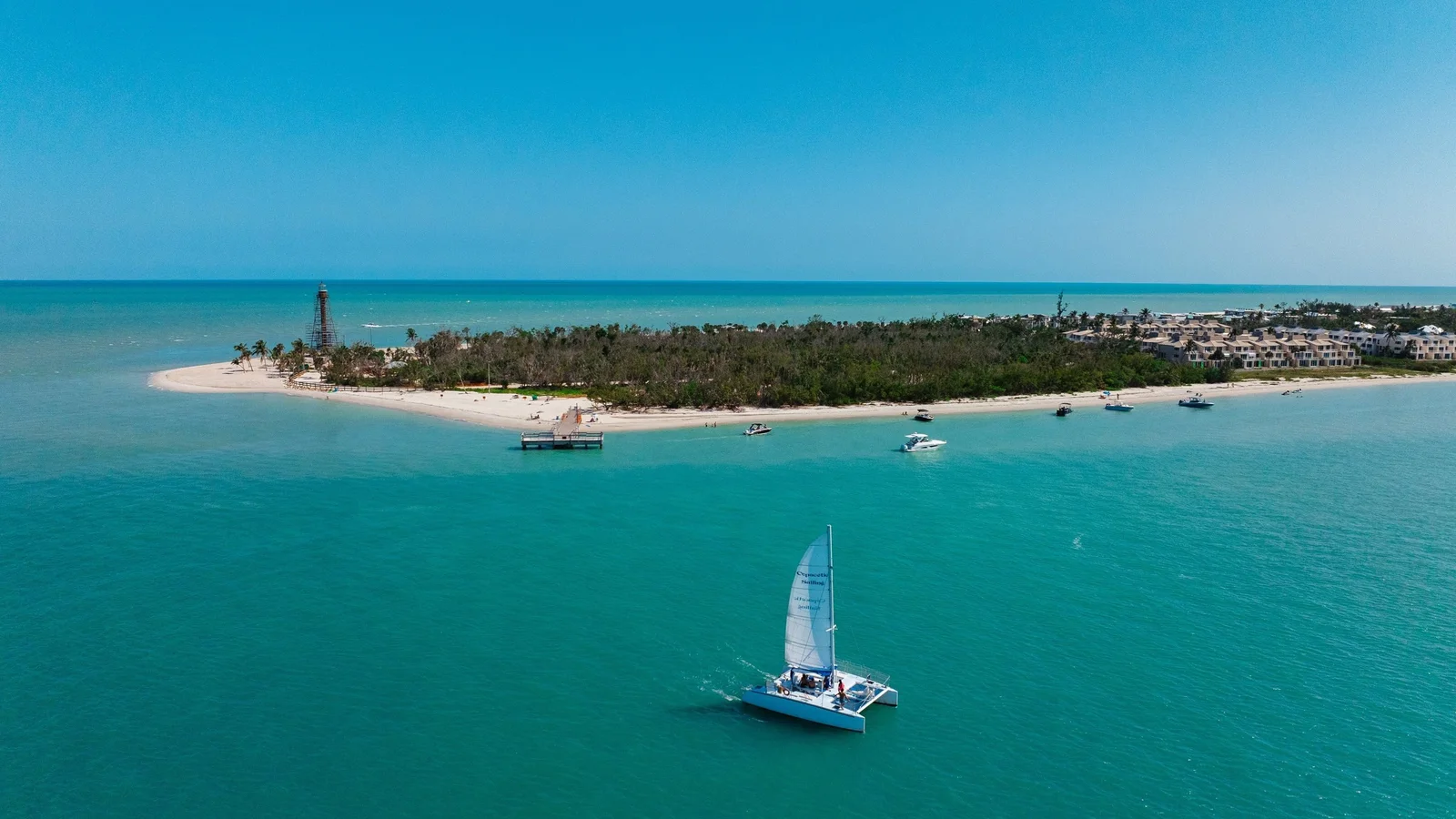 Aerial view of the eastern tip of Sanibel Island and its lighthouse with a sailboat in the Gulf