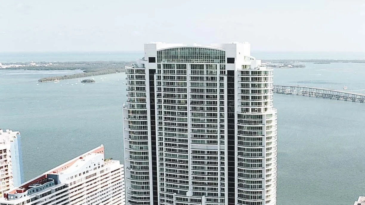 The white Santa Maria condo tower on Brickell Avenue, with Biscayne Bay and the Rickenbacker Causeway behind.