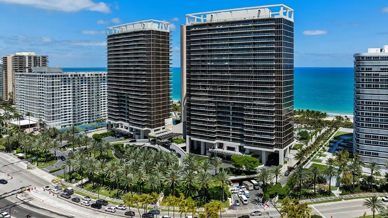 Dark glass towers of the St. Regis Bal Harbour on Collins Avenue, with the ocean behind
