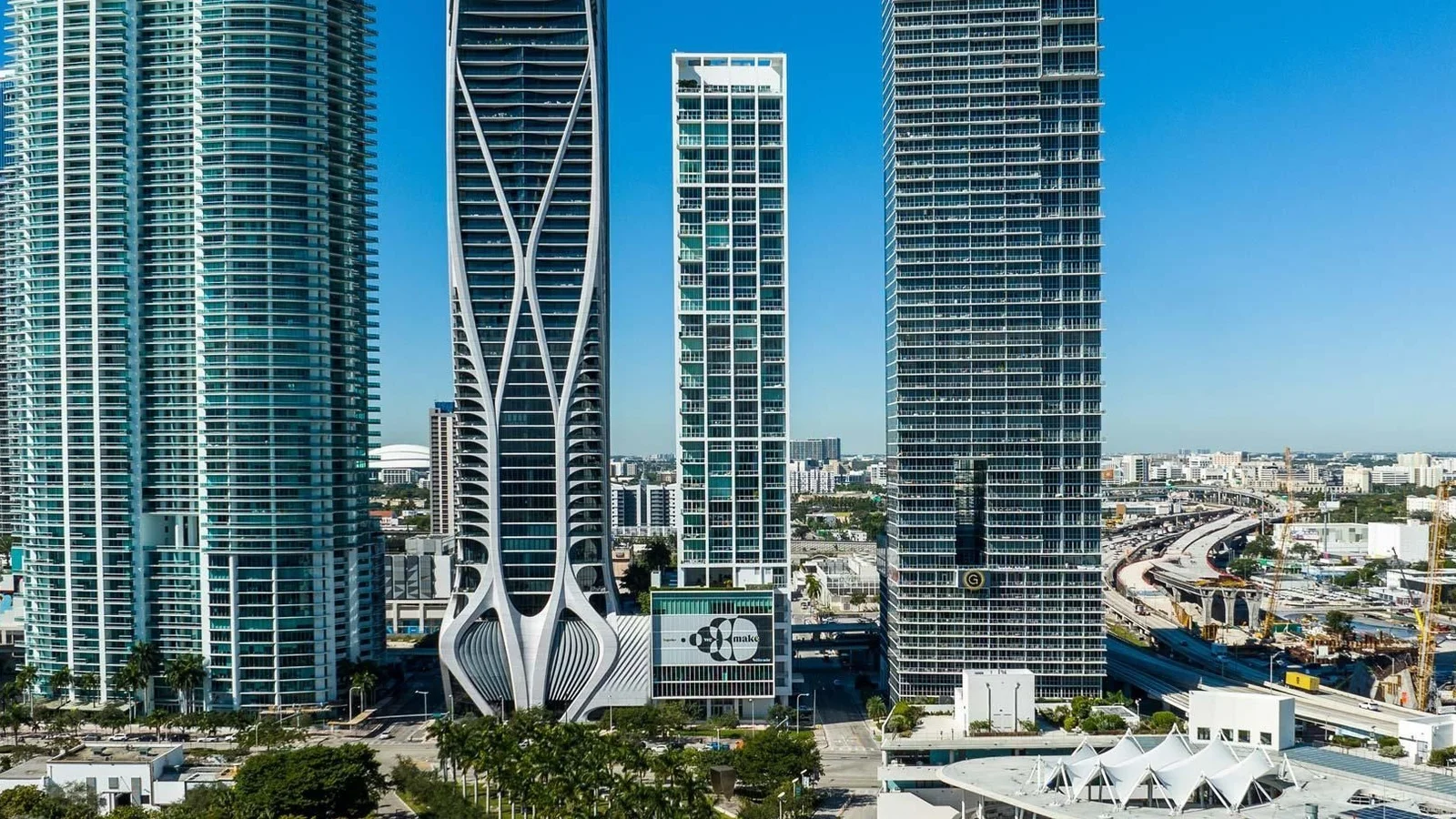 The slim Ten Museum Park tower beside the white exoskeleton of One Thousand Museum and other high-rises on Biscayne Boulevard.
