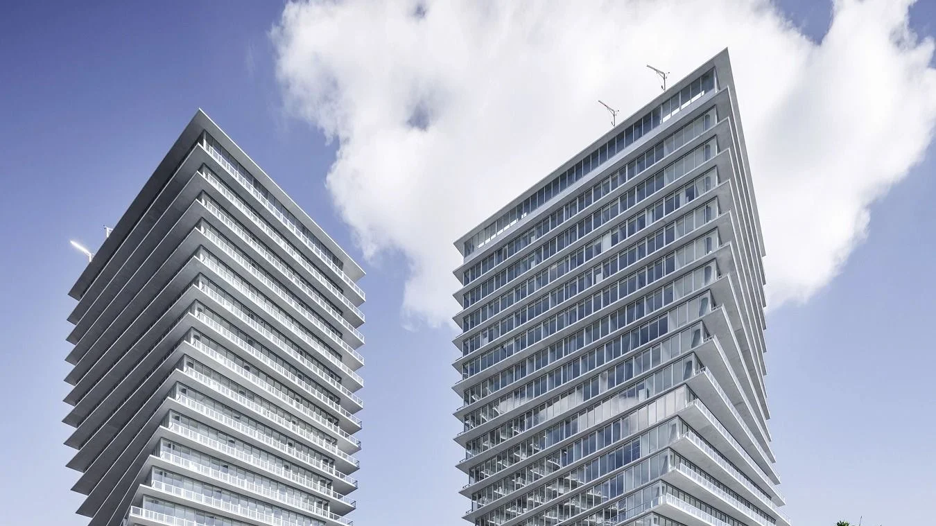The two twisting glass towers of Grove at Grand Bay in Coconut Grove, a Terra project, against a blue sky with white clouds.