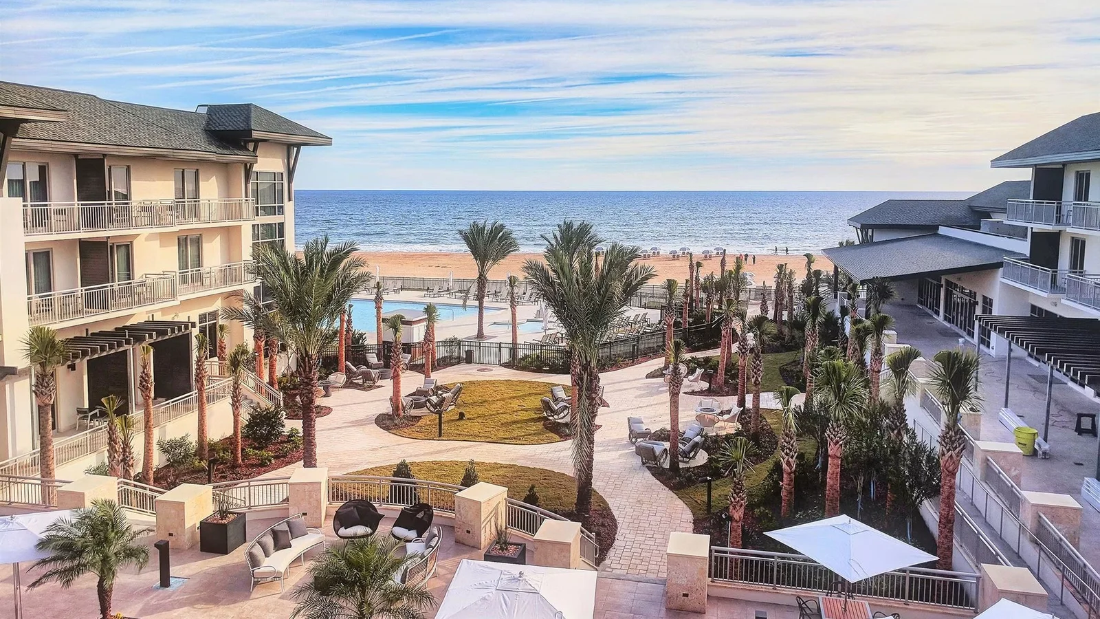 Beachfront hotel courtyard with palms and pool facing the ocean at St. Augustine Beach.