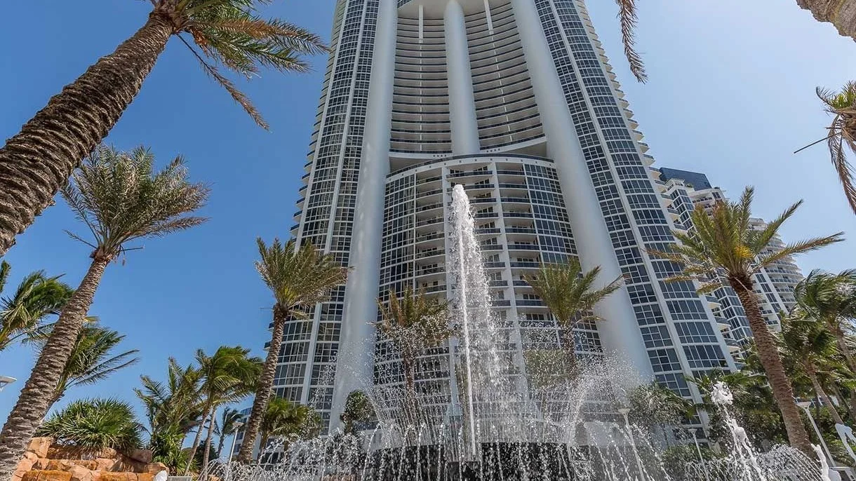 Trump Palace tower seen from below, with palm trees and the entrance fountain in the foreground