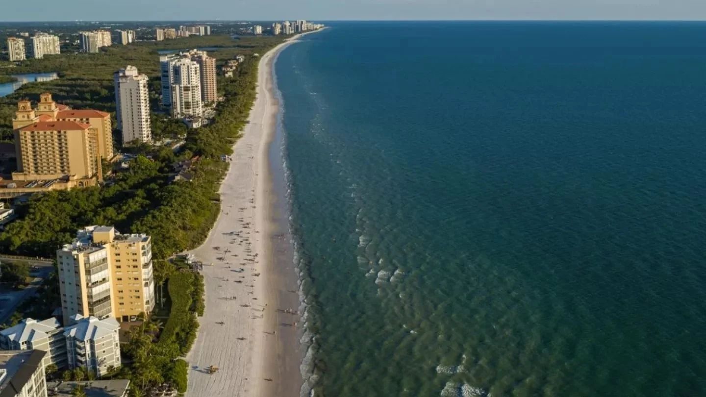 Aerial view of Vanderbilt Beach in Naples with condominium towers and a beach resort along the shore