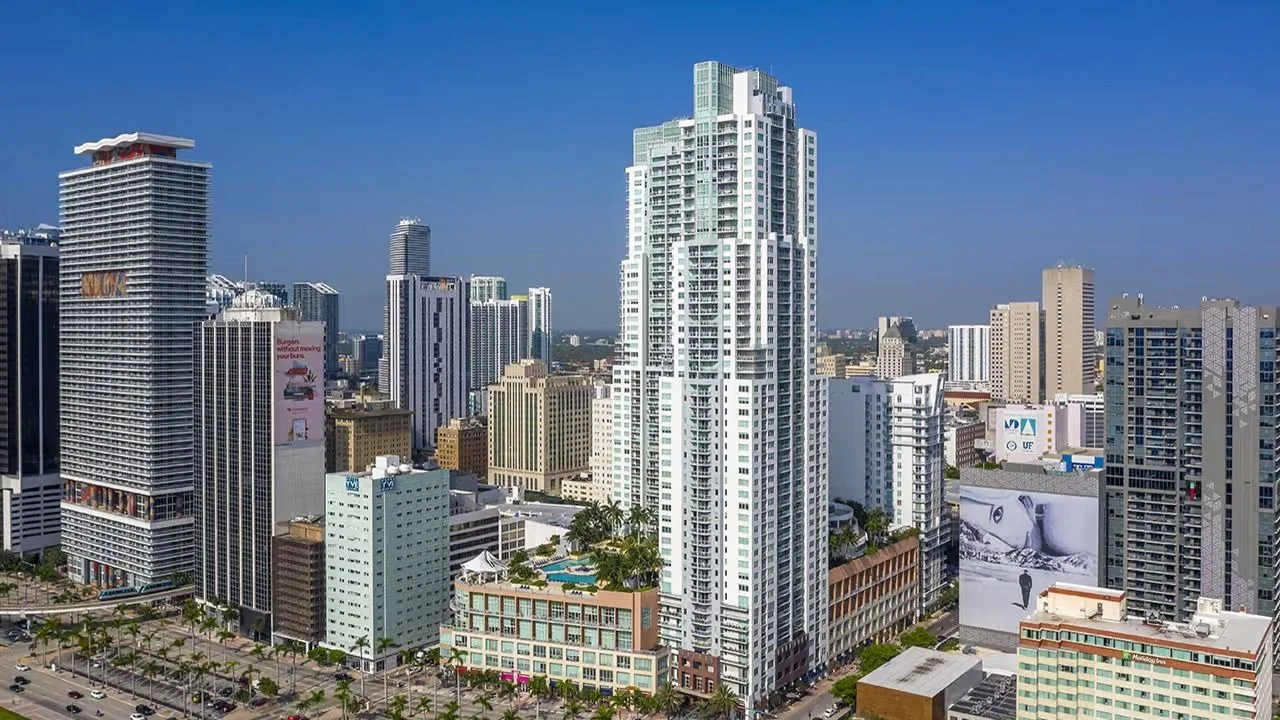 The white Vizcayne tower with its stepped glass crown rising above Biscayne Boulevard and neighbouring buildings in Downtown Miami.