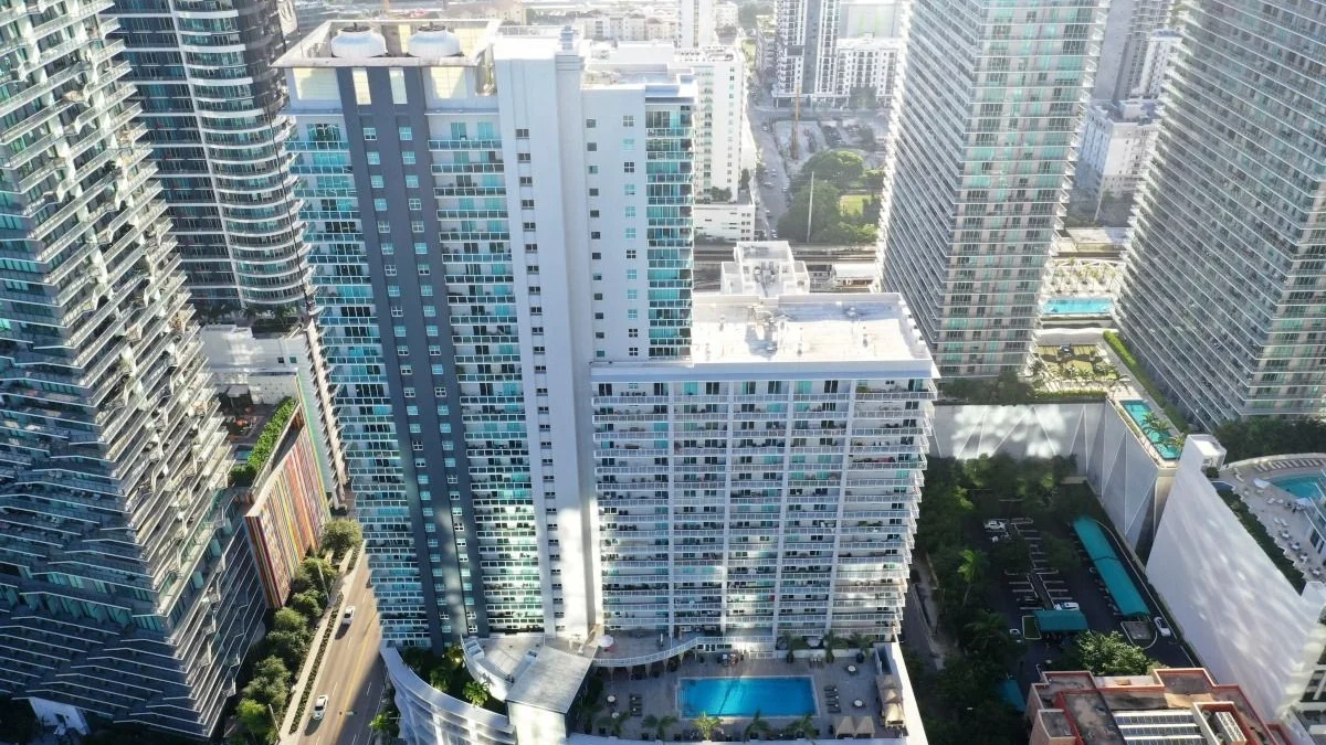 Aerial view of the Vue at Brickell tower and its pool deck between taller Brickell towers.