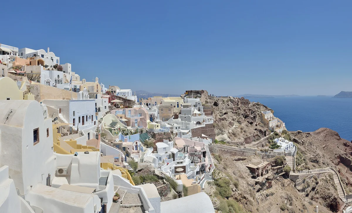 Whitewashed terraces stepping down a caldera cliff above deep blue water