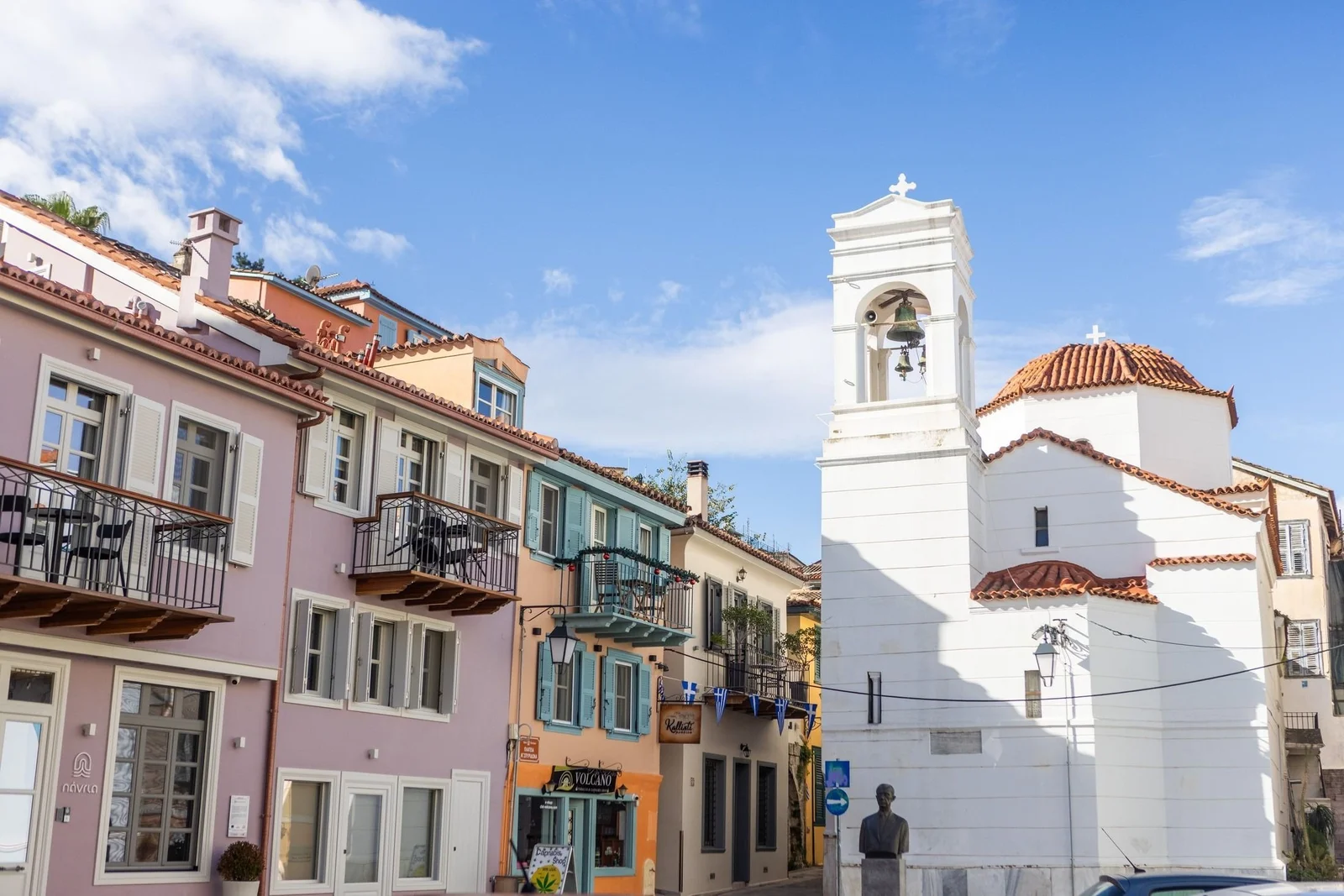 Pastel townhouses and a white church bell tower in Nafplio