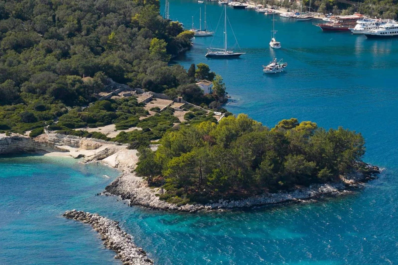 Aerial view of a wooded bay with sailing boats on Paxos