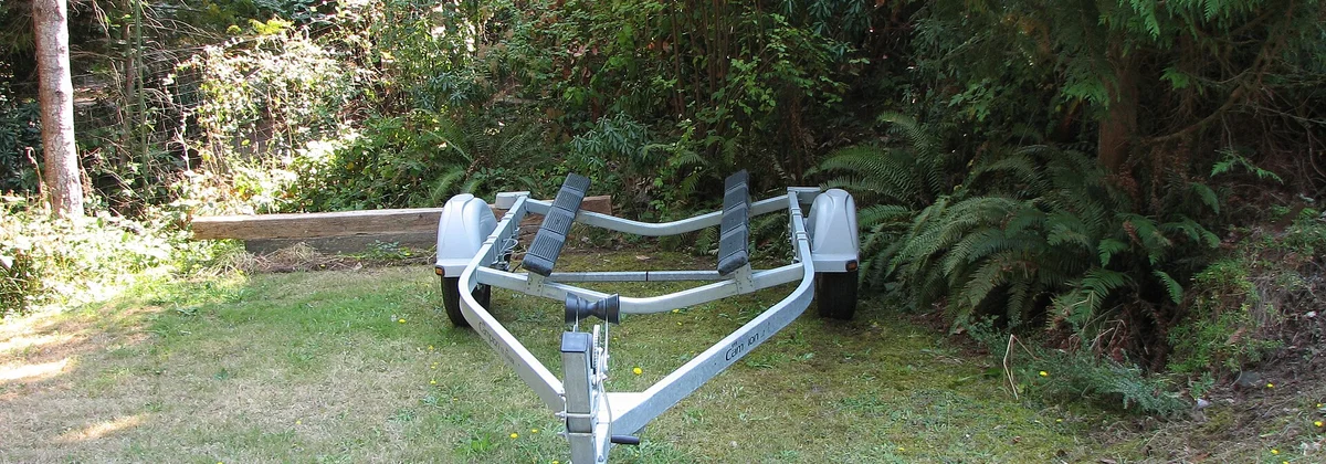 An empty boat trailer with its bunks and wheels visible