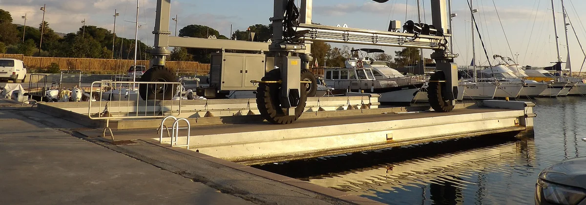 A boat lifted out of the water in a travel lift at a marina