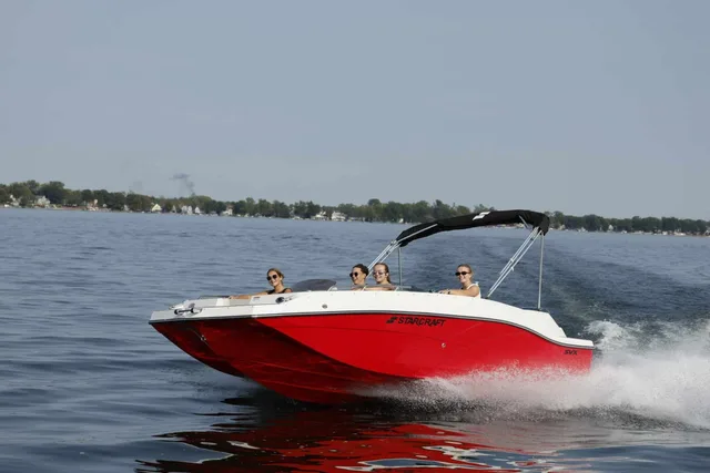 Starcraft deck boat with a bimini top cruising on a lake with passengers