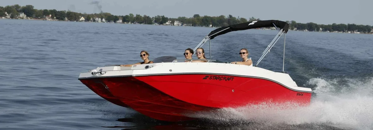 Starcraft deck boat with a bimini top cruising on a lake with passengers